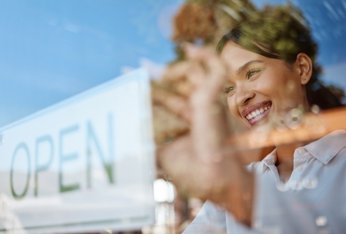 Woman smiles as she flips open sign