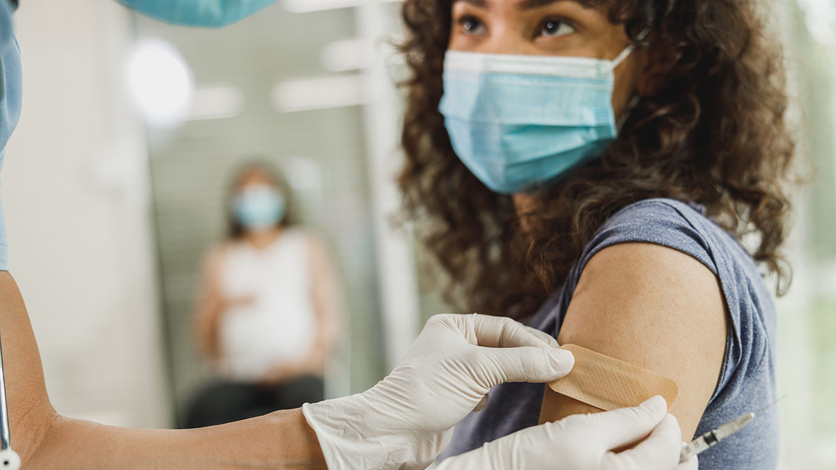 Y oung woman bandaged by medical professional after receiving vaccination